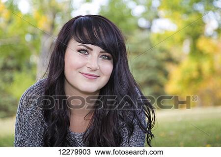 Stock Image - Portrait of a beautiful young woman outdoors in a city park in autumn; St. Albert, Alberta, Canada. Fotosearch