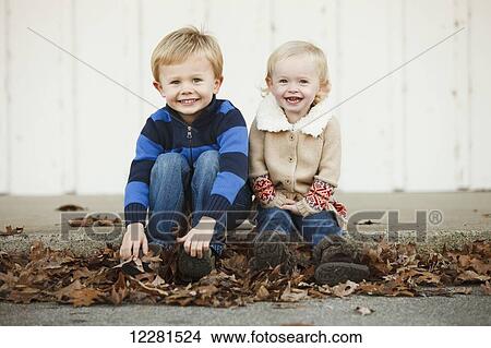 Portrait of a young boy and girl sitting among fallen autumn leaves; Nashville, Tennessee, United States of America View Large Photo Image Picture - Portrait of a young boy and girl sitting among fallen autumn leaves; Nashville, Tennessee, United States of America. Fotosearch