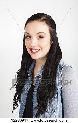 Stock Photo - Portrait of a young woman with long dark hair on a white background; Alberta, Canada. Fotosearch
