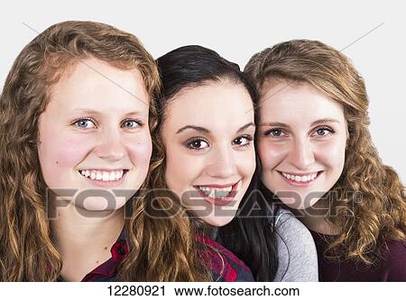 Stock Image - Portrait of three young women on a white background; Alberta, Canada. Fotosearch