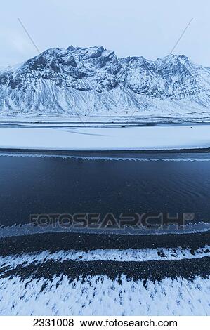 Snow Covered Landscape Along The Eastern Shore Of Iceland As A Stream Flows Gently Past With Ice Forming Along The Shore Of It; Iceland View Large Photo Image Stock Photo - Snow Covered Landscape Along The Eastern Shore Of Iceland As A Stream Flows Gently Past With Ice Forming Along The Shore Of It; Iceland. Fotosearch