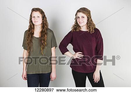 Stock Photo - Studio portrait of two young women against a white background; Alberta, Canada. Fotosearch