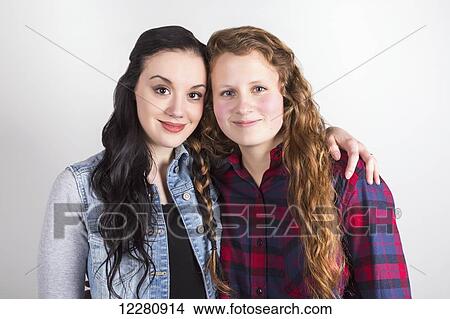 Picture - Studio portrait of two young women with their hair braided together; Alberta, Canada. Fotosearch