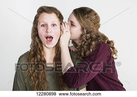 Studio shot of one friend telling a secret to another friend, on a white background; Alberta, Canada View Large Photo Image Stock Photo - Studio shot of one friend telling a secret to another friend, on a white background; Alberta, Canada. Fotosearch