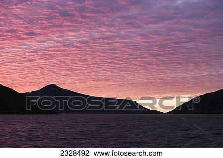 Stock Image - Sunset Behind A Ridgeline From The Water Near Cold Bay; Southwest Alaska, United States Of America. Fotosearch
