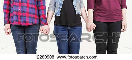 Three young women holding hands committed to teamwork; Alberta, Canada View Large Photo Image Stock Photo - Three young women holding hands committed to teamwork; Alberta, Canada. Fotosearch