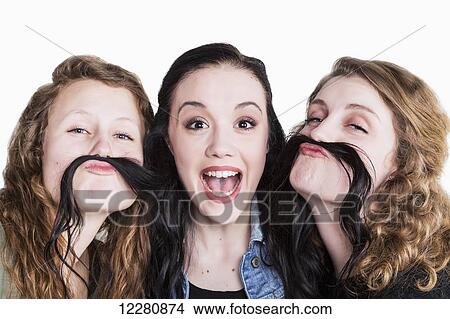 Picture - Three young women in a humorous pose using long hair for a moustache; Alberta, Canada. Fotosearch