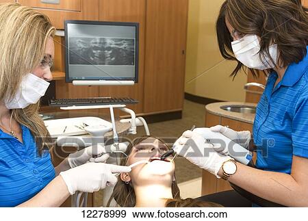 Two dental assistants performing dental procedure on female patient; Edmonton, Alberta, Canada View Large Photo Image Stock Photo - Two dental assistants performing dental procedure on female patient; Edmonton, Alberta, Canada. Fotosearch