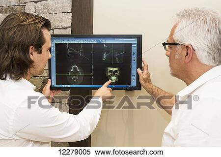 Stock Photography - Two dentists reviewing images and consulting over dental procedure options; Edmonton, Alberta, Canada. Fotosearch