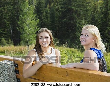 Two girlfriends spending time together sitting on a park bench; Edmonton, Alberta, Canada View Large Photo Image Stock Image - Two girlfriends spending time together sitting on a park bench; Edmonton, Alberta, Canada. Fotosearch