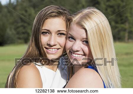 Stock Photo - Two girlfriends spending time together in a park and posing for a picture; Edmonton, Alberta, Canada. Fotosearch
