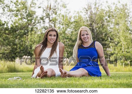 Two girlfriends spending time together in a park in their dresses; Edmonton, Alberta, Canada View Large Photo Image Stock Photography - Two girlfriends spending time together in a park in their dresses; Edmonton, Alberta, Canada. Fotosearch