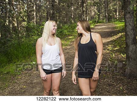 Two teenage girlfriends walking and talking together on a path in a wooded park; Edmonton, Alberta, Canada View Large Photo Image Stock Image - Two teenage girlfriends walking and talking together on a path in a wooded park; Edmonton, Alberta, Canada. Fotosearch