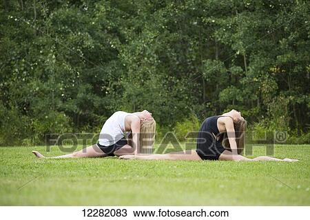 Two teenage gymnasts practicing their routines outdoors in a park, doing splits with head back; Edmonton, Alberta, Canada View Large Photo Image Stock Image - Two teenage gymnasts practicing their routines outdoors in a park, doing splits with head back; Edmonton, Alberta, Canada. Fotosearch