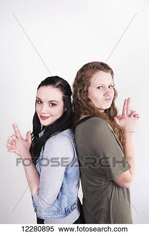 Stock Photography - Two young women pretending to have smoking guns; Alberta, Canada. Fotosearch