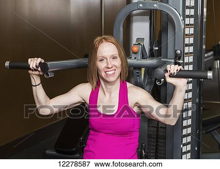 Young disabled woman using a shoulder press to rehabilitate herself from a spinal injury; Edmonton, Alberta, Canada View Large Photo Image Stock Photo - Young disabled woman using a shoulder press to rehabilitate herself from a spinal injury; Edmonton, Alberta, Canada. Fotosearch