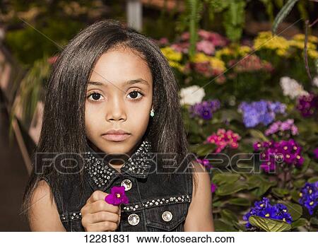 Stock Image - Young girl holding a flower in a shopping centre; St. Albert, Alberta, Canada. Fotosearch