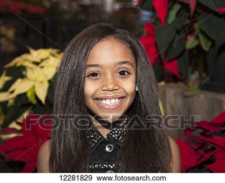 Stock Photo - Young girl posing in front of poinsettia plants in a shopping centre; St. Albert, Alberta, Canada. Fotosearch