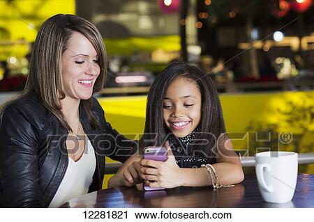 Young mother and her daughter in a cafe looking at a smart phone while taking a break from shopping; St. Albert, Alberta, Canada View Large Photo Image Stock Image - Young mother and her daughter in a cafe looking at a smart phone while taking a break from shopping; St. Albert, Alberta, Canada. Fotosearch