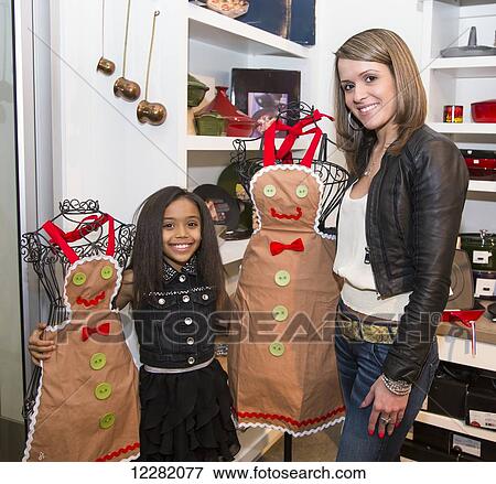 Stock Photo - Young mother and her daughter shopping at a kitchen store looking at aprons; St. Albert, Alberta, Canada. Fotosearch