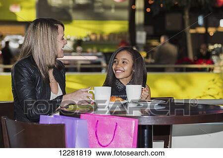 Stock Photo - Young mother and her daughter stopping for a snack while shopping; St. Albert, Alberta, Canada. Fotosearch