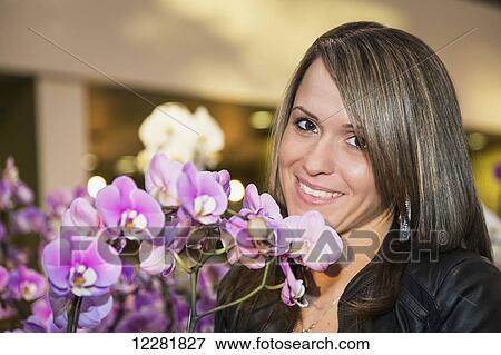 Young woman admiring flowers in a greenhouse section of a shopping complex; St. Albert, Alberta, Canada View Large Photo Image Stock Photo - Young woman admiring flowers in a greenhouse section of a shopping complex; St. Albert, Alberta, Canada. Fotosearch