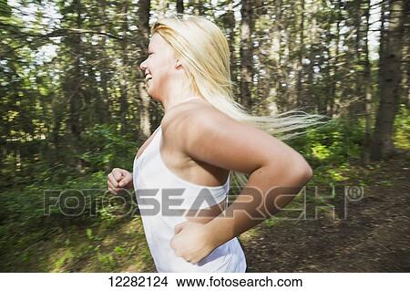 Picture - Young woman jogging in a park; Edmonton, Alberta, Canada. Fotosearch
