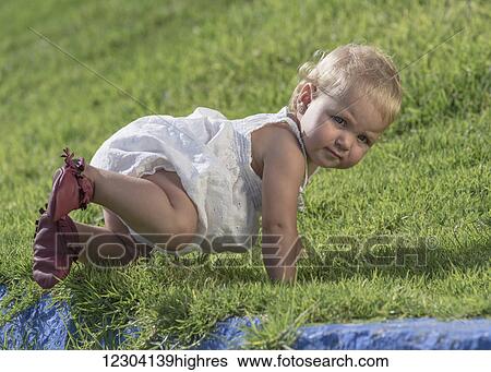 Stock Photograph - A baby crawls on the grass; Tarifa, Cadiz, Andalusia, Spain. Fotosearch