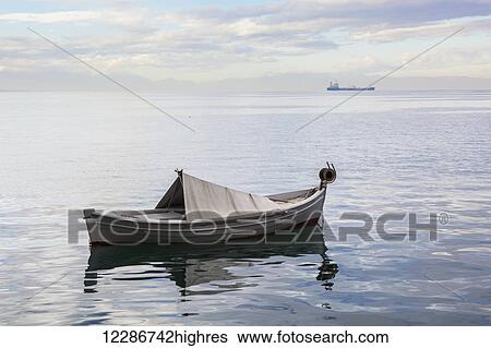 A boat floating on the tranquil Aegean Sea with a ship in the distance; Thessaloniki, Greece View Large Photo Image Stock Photograph - A boat floating on the tranquil Aegean Sea with a ship in the distance; Thessaloniki, Greece. Fotosearch