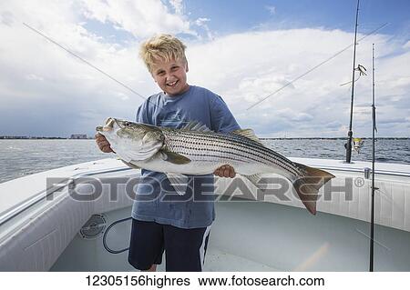 Stock Photograph - A boy holds a large fish on a boat off the Boston harbour; Boston, Massachusetts, United States of America. Fotosearch