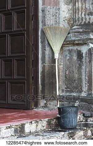 Stock Photograph - A broom and pail sitting on a concrete step in a doorway; San Miguel de Allende, Guanajuato, Mexico. Fotosearch