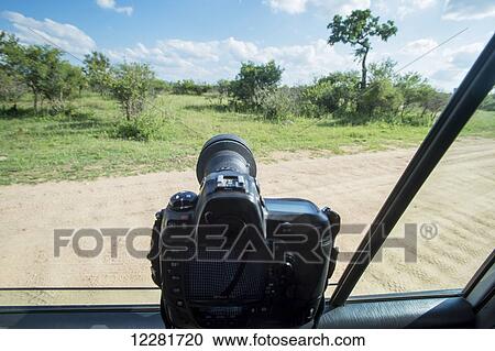 Stock Image - A camera propped on the window of a vehicle pointing out into Kruger National Park; South Africa. Fotosearch
