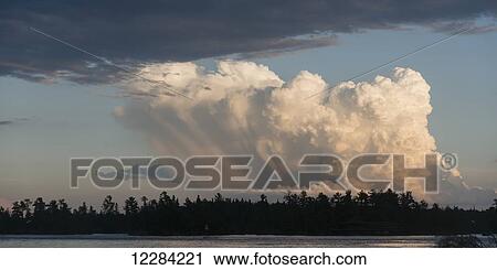 A cloud formation glowing with sunlight over a silhouette of forest and a lake; Ontario, Canada View Large Photo Image Stock Image - A cloud formation glowing with sunlight over a silhouette of forest and a lake; Ontario, Canada. Fotosearch