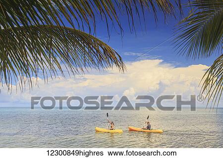 Stock Photograph - A couple using kayaks at Saint Georges Caye Resort; Belize City, Belize. Fotosearch