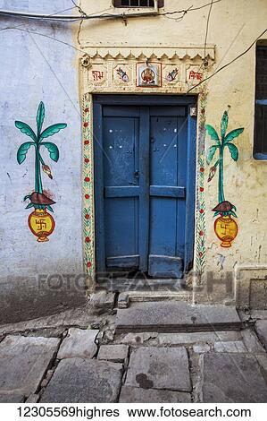 Stock Photograph - A door to a home painted with local Hindu motifs, including hindu swastikas; Varanasi, India. Fotosearch