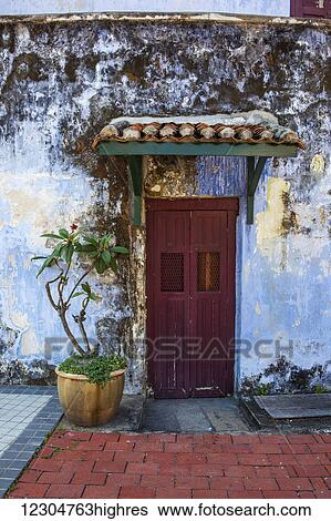 Stock Photograph - A faded red door sits surrounded by a weathered blue wall in downtown Georgetown; Georgetown, Penang, Malaysia. Fotosearch