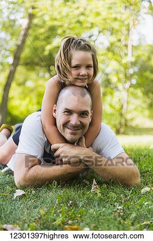 Stock Photograph - A father and daughter posing and spending quality time together in a park during a family outing; Edmonton, Alberta, Canada. Fotosearch