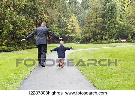 Stock Photograph - A father and son walking down a path in Bear Creek Park; Surrey, British Columbia, Canada. Fotosearch