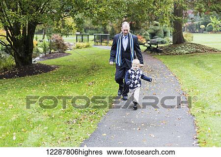 Stock Photograph - A father and son walking on a path in a park; Surrey, British Columbia, Canada. Fotosearch