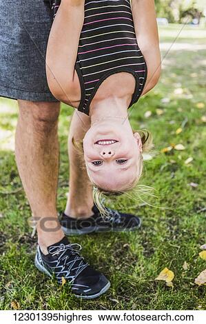 A father hanging his daughter upside down and playing around in a park during a family outing; Edmonton, Alberta, Canada View Large Photo Image Stock Photograph - A father hanging his daughter upside down and playing around in a park during a family outing; Edmonton, Alberta, Canada. Fotosearch