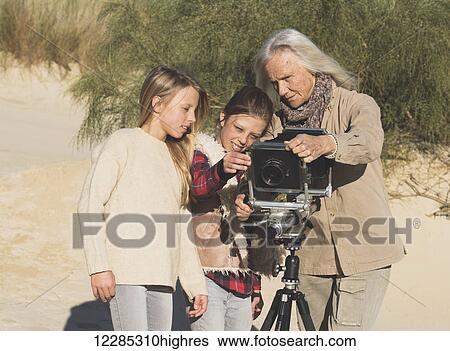 A female photographer shows two young girls images on a camera with tripod on the beach; Tarifa, Cadiz, Andalusia, Spain View Large Photo Image Stock Photograph - A female photographer shows two young girls images on a camera with tripod on the beach; Tarifa, Cadiz, Andalusia, Spain. Fotosearch