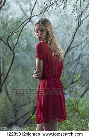 A girl wearing a red dress with blond hair looking unsure as she walks among trees; Tarifa, Cadiz, Andalusia, Spain View Large Photo Image Stock Photograph - A girl wearing a red dress with blond hair looking unsure as she walks among trees; Tarifa, Cadiz, Andalusia, Spain. Fotosearch