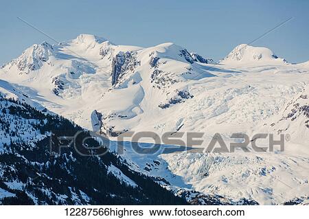 A glacier hangs in a valley below jagged snow covered peaks in Kings Bay, Prince William Sound; Whittier, Alaska, United States of America View Large Photo Image Stock Photograph - A glacier hangs in a valley below jagged snow covered peaks in Kings Bay, Prince William Sound; Whittier, Alaska, United States of America. Fotosearch