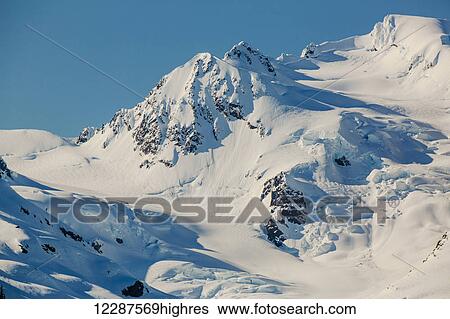 A glacier hangs in a valley below jagged snow covered peaks in Kings Bay, Prince William Sound; Whittier, Alaska, United States of America View Large Photo Image Stock Photograph - A glacier hangs in a valley below jagged snow covered peaks in Kings Bay, Prince William Sound; Whittier, Alaska, United States of America. Fotosearch