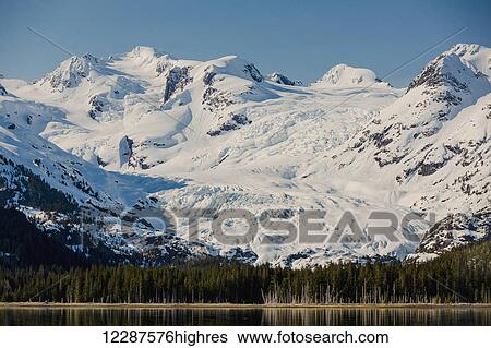 A glacier hangs in a valley below jagged snow covered peaks in Kings Bay, Prince William Sound; Whittier, Alaska, United States of America View Large Photo Image Stock Photograph - A glacier hangs in a valley below jagged snow covered peaks in Kings Bay, Prince William Sound; Whittier, Alaska, United States of America. Fotosearch