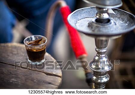Stock Photograph - A glass of Turkish coffee sits by a sheesha in a small village near Luxor; Egypt. Fotosearch