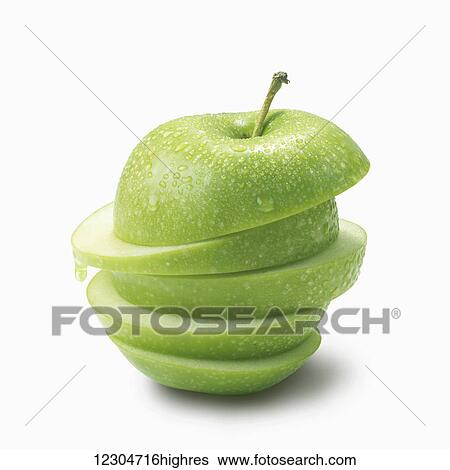Stock Photograph - A green apple cut into slices and piled on a white background; Toronto, Ontario, Canada. Fotosearch