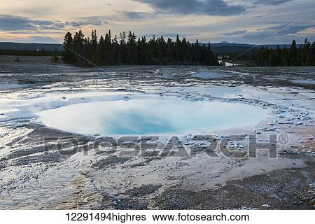 Stock Photograph - A hot spring pool reflects evening light in Yellowstone National Park; Wyoming, United States of America. Fotosearch