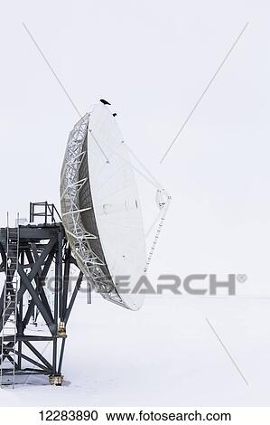 Stock Image - A large satellite dish points out to barren sea ice, Barrow, North Slope, Arctic Alaska, USA, Winter. Fotosearch