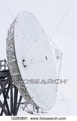 Stock Image - A large satellite dish points out to barren sea ice, Barrow, North Slope, Arctic Alaska, USA, Winter. Fotosearch